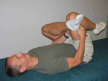 Person demonstrating piriformis stretch. 90+ hip/knee flexion right leg; lateral rotation left leg. 